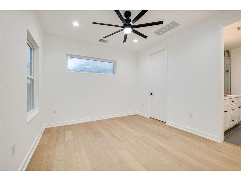 Retreat to the upstairs primary bedroom with a striking black ceiling fan, ambient recessed lighting, and a vast walk-in closet.