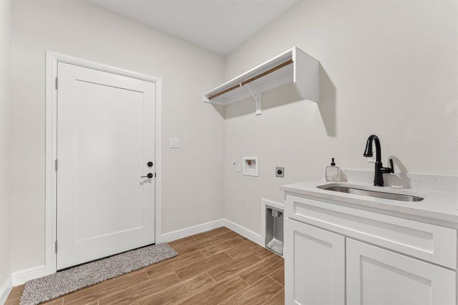 Washroom with wood tiled floors, electric dryer hookup, washer hookup, gas dryer hookup, and cabinet space