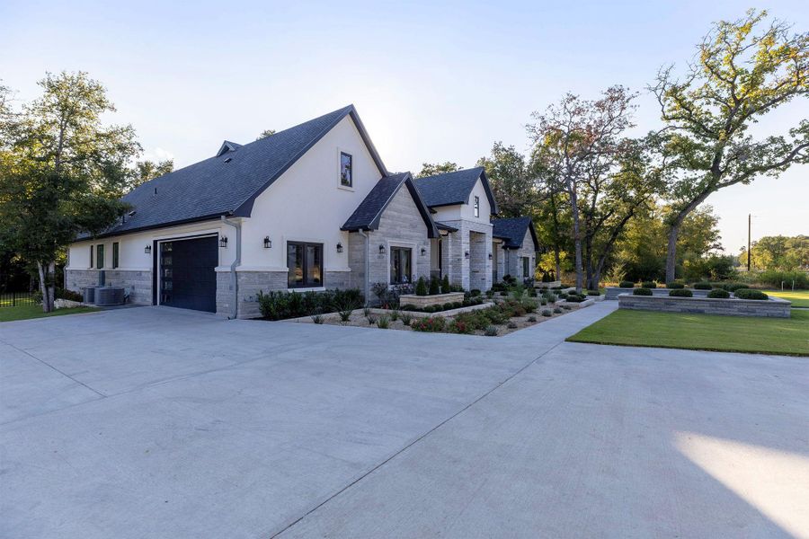 View of property exterior with concrete driveway, stone siding, stucco siding, an attached garage, and a lawn View of property exterior with concrete driveway, stone siding, stucco siding, an attached garage, and a lawn