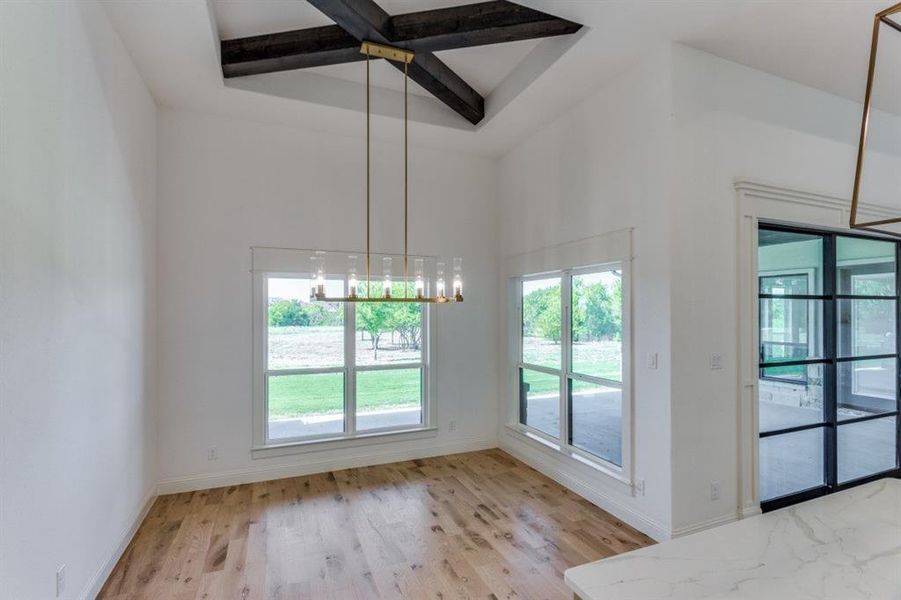 Dining room featuring beam ceiling, light hardwood / wood-style flooring, and a notable chandelier