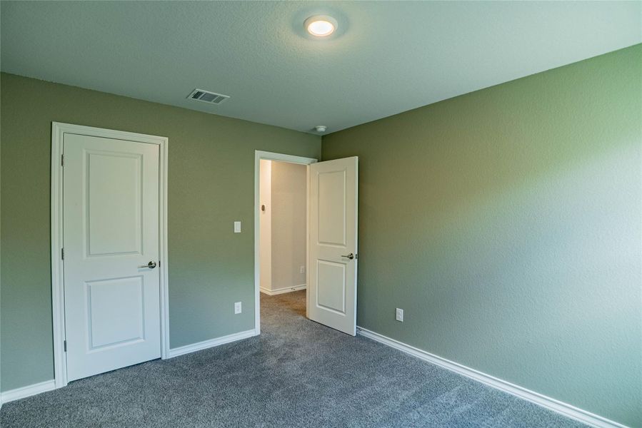 Unfurnished bedroom featuring dark carpet and baseboards Unfurnished bedroom featuring dark carpet and baseboards