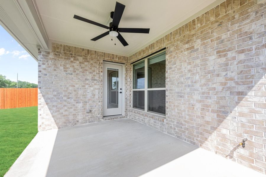 Covered back patio with ceiling fan, brick exterior, concrete floor, and fenced yard Covered back patio with ceiling fan, brick exterior, concrete floor, and fenced yard