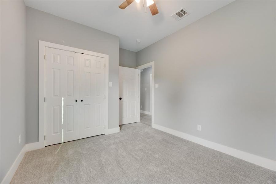 Unfurnished bedroom with light colored carpet, a closet, and ceiling fan