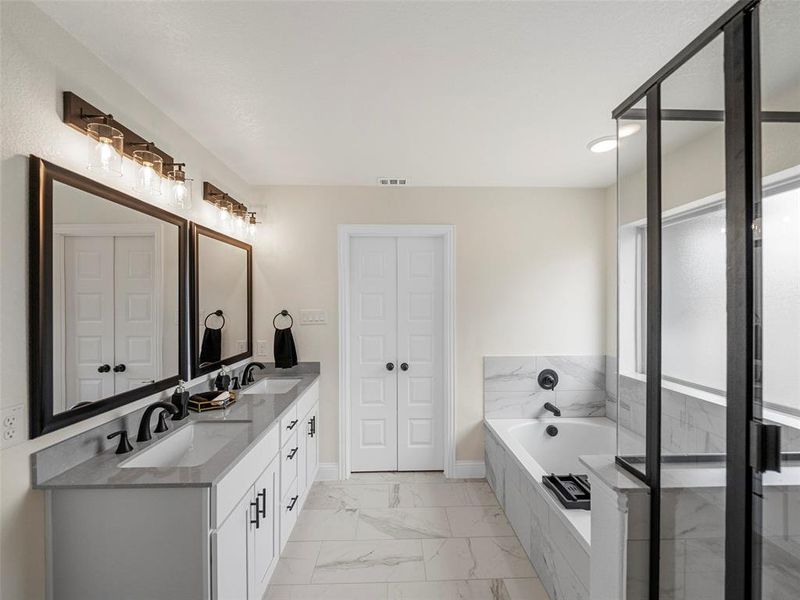 Bathroom with marble finish floors, a bath, double vanity, and a closet Bathroom with marble finish floors, a bath, double vanity, and a closet