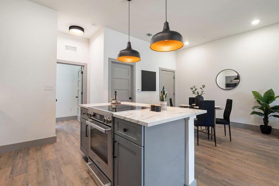 Kitchen featuring gray cabinetry, stainless steel electric range, light stone counters, pendant lighting, and dark wood finished floors