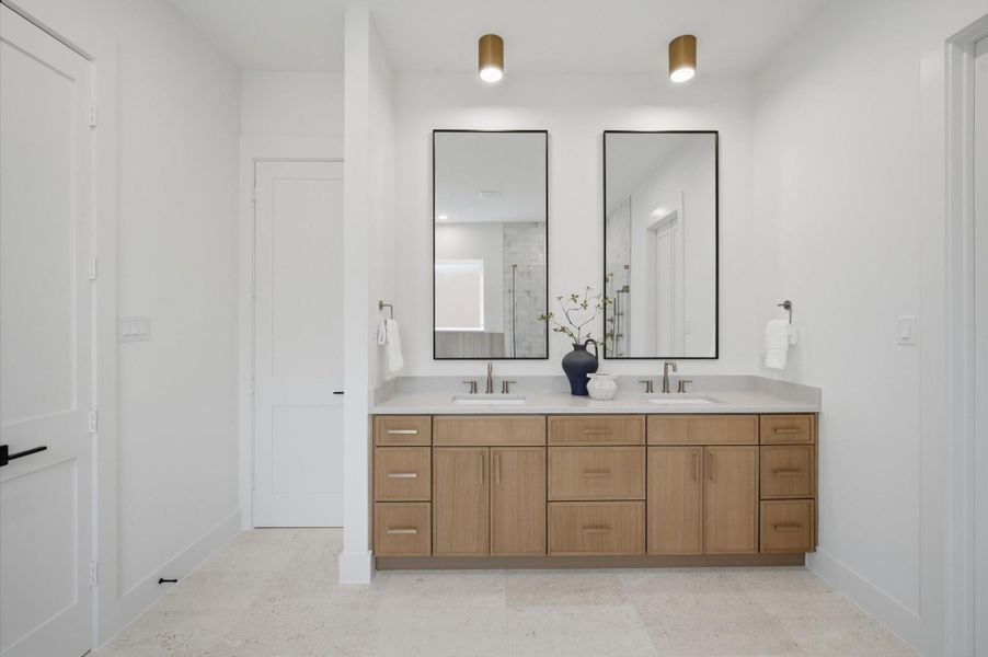 Dual sinks with quartz countertops enhance the luxurious primary bathroom.