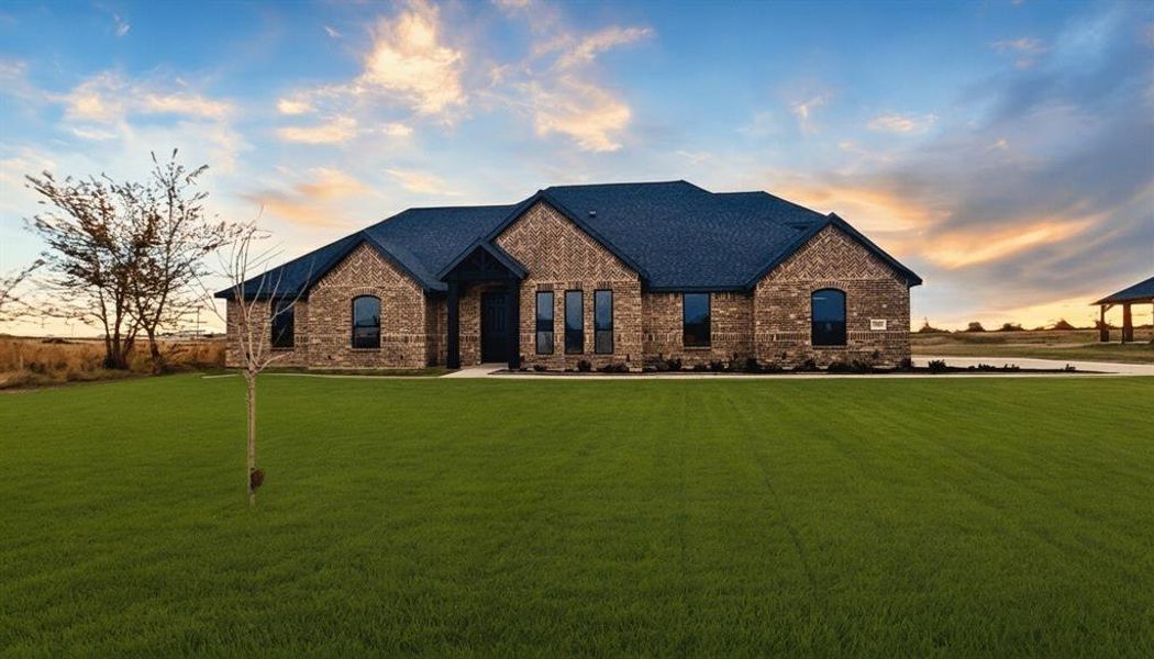 French country style house featuring brick siding and a yard
