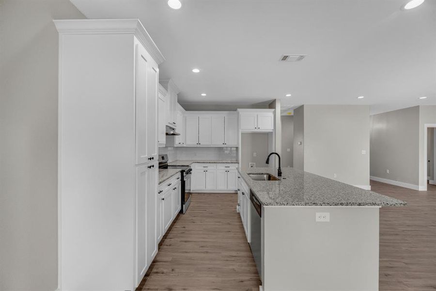 Kitchen with white cabinets, appliances with stainless steel finishes, an island with sink, and sink