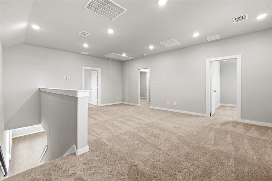Carpeted spare room featuring vaulted ceiling