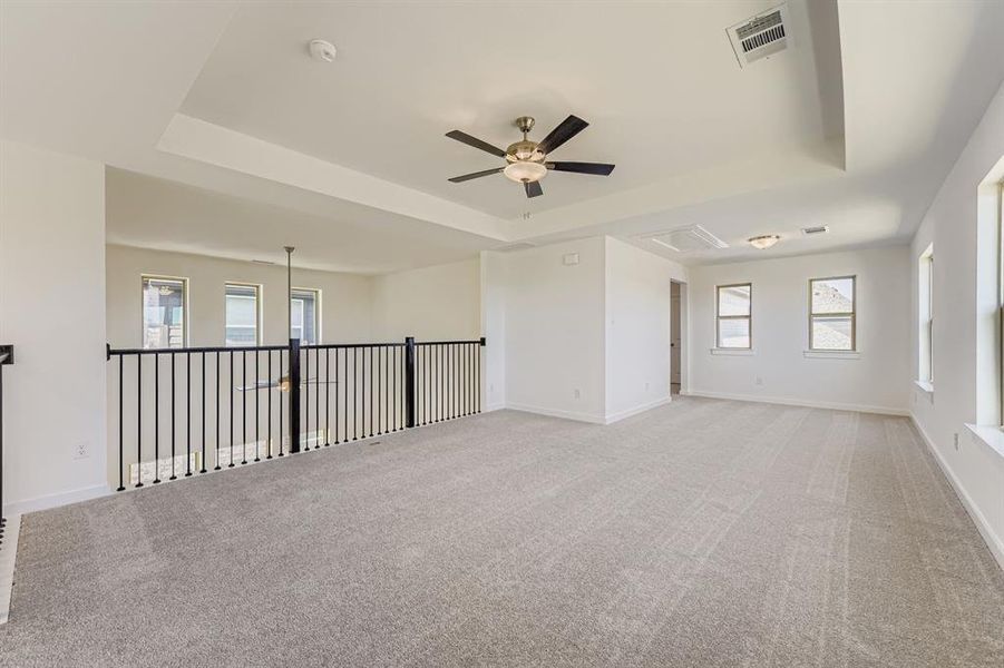 Empty room featuring a tray ceiling, plenty of natural light, and light colored carpet Empty room featuring a tray ceiling, plenty of natural light, and light colored carpet