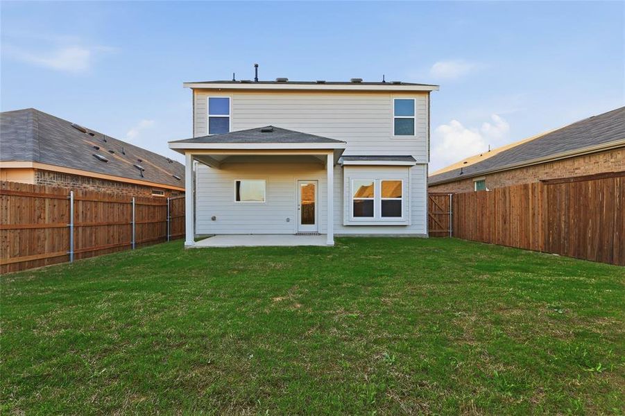 Expansive grassy backyard featuring a covered patio, full privacy fencing, and a rear entrance Expansive grassy backyard featuring a covered patio, full privacy fencing, and a rear entrance