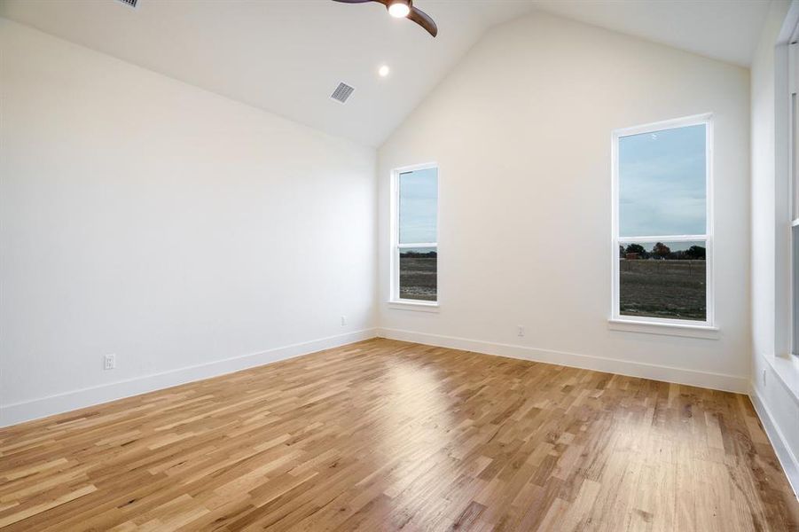 Spare room with high vaulted ceiling, light hardwood / wood-style flooring, and ceiling fan