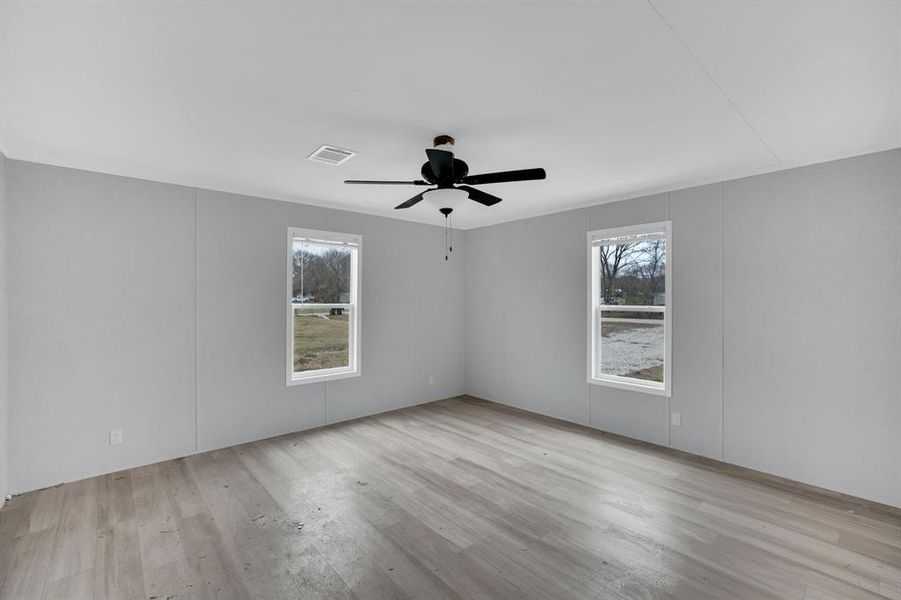 Empty room featuring light wood finished floors, a decorative wall, and a ceiling fan