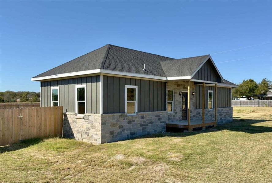 View of home's exterior featuring board and batten siding, stone siding, roof with shingles, and covered porch View of home's exterior featuring board and batten siding, stone siding, roof with shingles, and covered porch