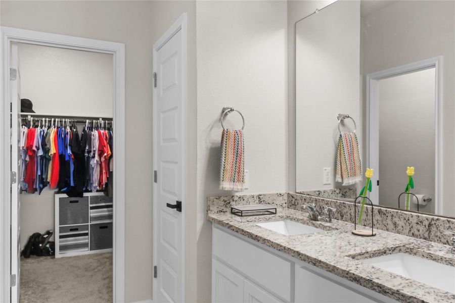 Full bathroom with double vanity and a walk in closet