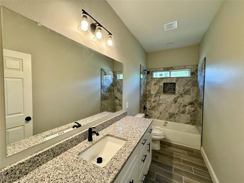 Full bathroom with vanity, tile patterned flooring, tiled shower / bath, and toilet