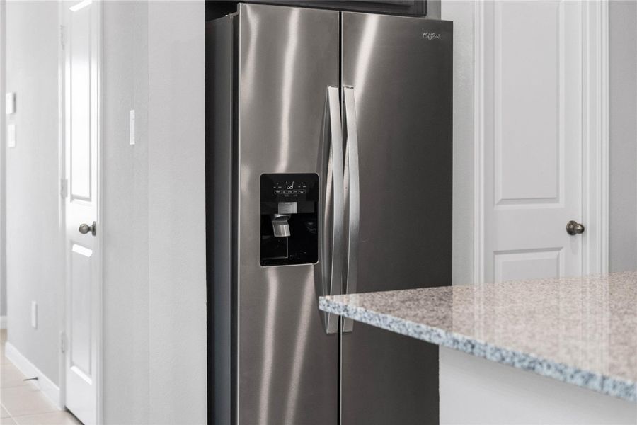 Kitchen comes equipped with a side-by-side Whirlpool refrigerator.