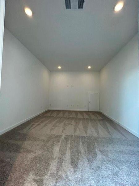 Spacious room featuring neutral carpet flooring, recessed ceiling lighting, a white painted interior door, and white baseboards Spacious room featuring neutral carpet flooring, recessed ceiling lighting, a white painted interior door, and white baseboards