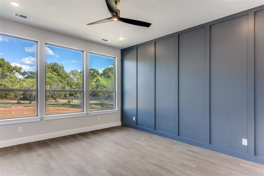 Empty room with light wood-type flooring, ceiling fan, recessed lighting, and a decorative wall Empty room with light wood-type flooring, ceiling fan, recessed lighting, and a decorative wall