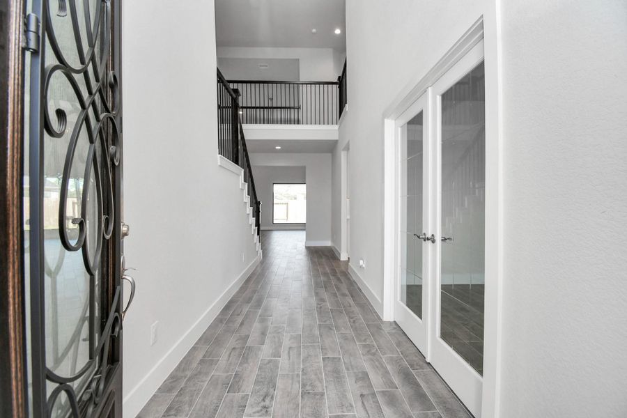 As you step into the threshold of this luxurious home, you'll soon be welcomed by an elegant glass door. Inside, soaring ceilings amplify the spaciousness, while the refined wood-look tile flooring and oversized baseboards exude sophistication and charm.