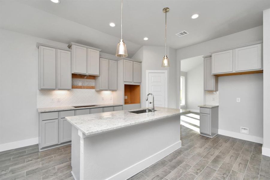 Discover another perspective of this stunning kitchen, generously appointed with an abundance of counter space. Sample photo of completed home with similar plan. As built color and selections will vary.