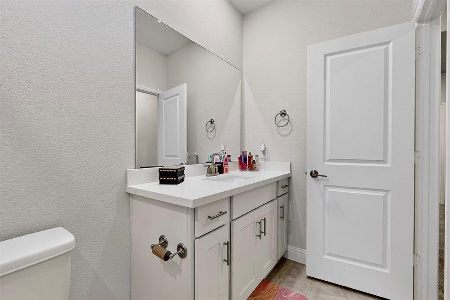Half bathroom with a textured wall and vanity