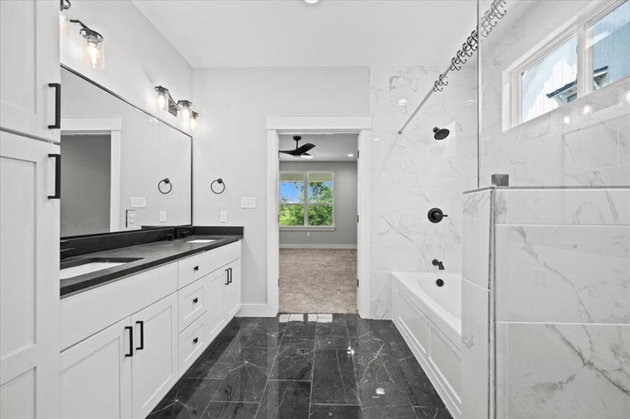 Full bathroom featuring marble finish flooring, double vanity, shower / bath combination, and a ceiling fan