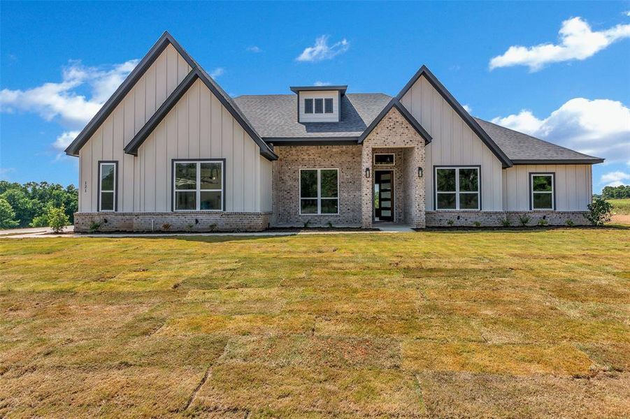 Modern farmhouse style home featuring a front lawn