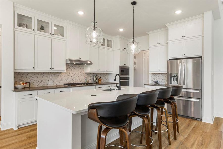 Kitchen featuring appliances with stainless steel finishes, under cabinet range hood, light wood finished floors, white cabinets, and recessed lighting Kitchen featuring appliances with stainless steel finishes, under cabinet range hood, light wood finished floors, white cabinets, and recessed lighting