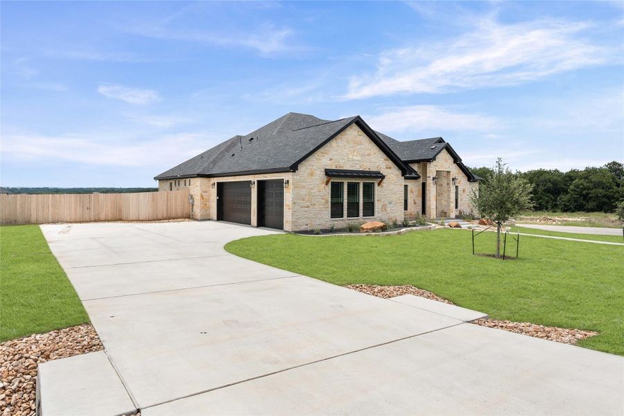 A spacious concrete driveway guides to this newly constructed home featuring an attached garage and stone exterior. A spacious concrete driveway guides to this newly constructed home featuring an attached garage and stone exterior.