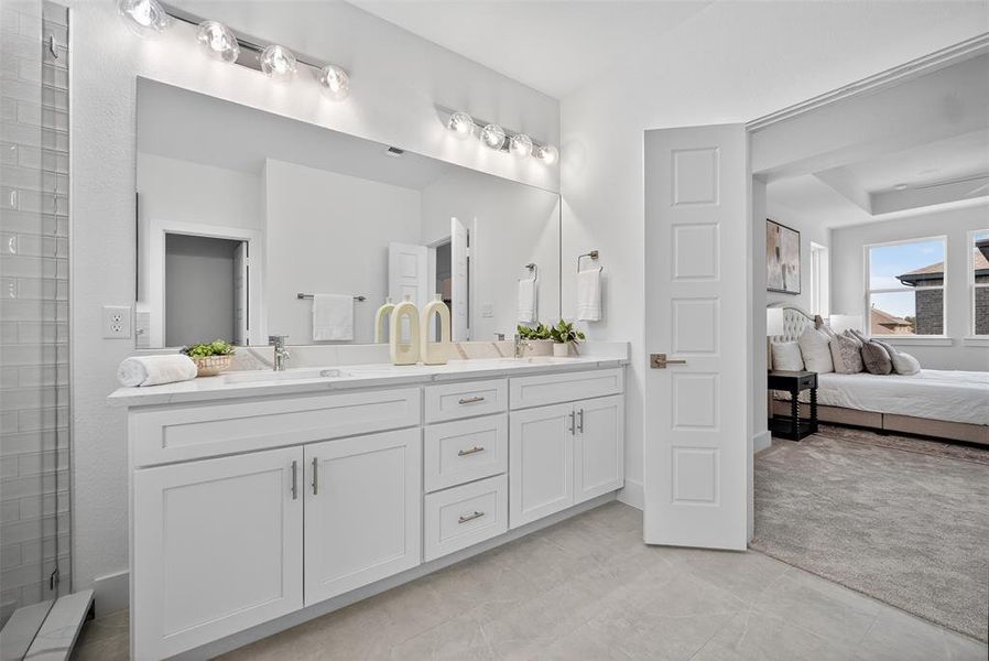 Ensuite bathroom with double vanity, a tile shower, and light tile patterned floors