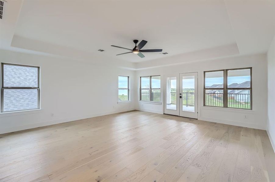 Spare room with light wood-type flooring, ceiling fan, and a raised ceiling