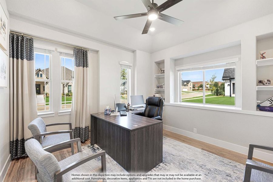 Home office with dark wood desk, ceiling fan, built-in shelves, and hardwood floors with large windows