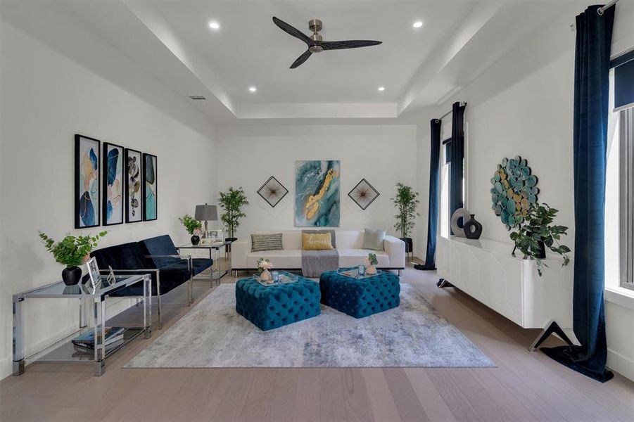 Living room featuring ceiling fan, a tray ceiling, and hardwood / wood-style floors