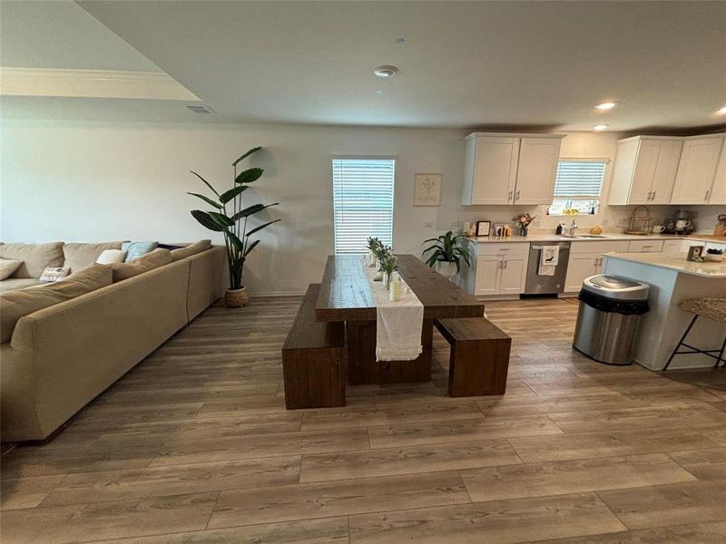 Kitchen with white cabinetry, a kitchen breakfast bar, dishwasher, light wood-type flooring, and open floor plan