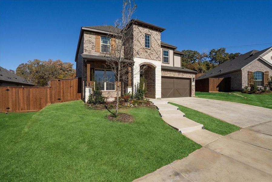 View of front facade featuring a garage and a front lawn