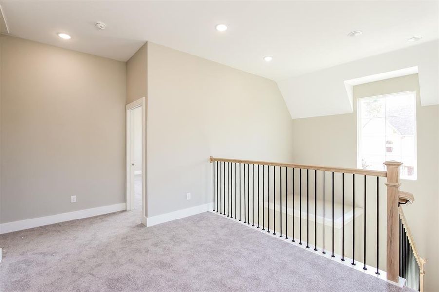 Unfurnished room with lofted ceiling and light carpet