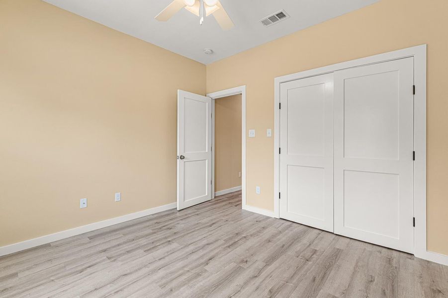 Unfurnished bedroom with wood finished floors, a closet, and a ceiling fan
