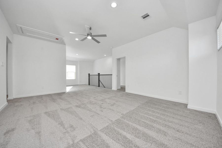 Come upstairs and relish a day of relaxation in this loft area! Ideal as an additional living space or game room, it boasts plush carpeting, high ceilings, custom paint, and windows that flood the area with abundant natural light. Sample photo of completed home with similar floor plan. Actual colors and selections may vary.