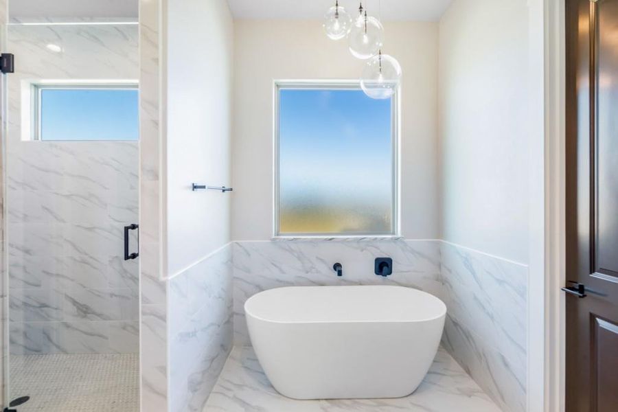 Bathroom featuring shower with separate bathtub and tile walls