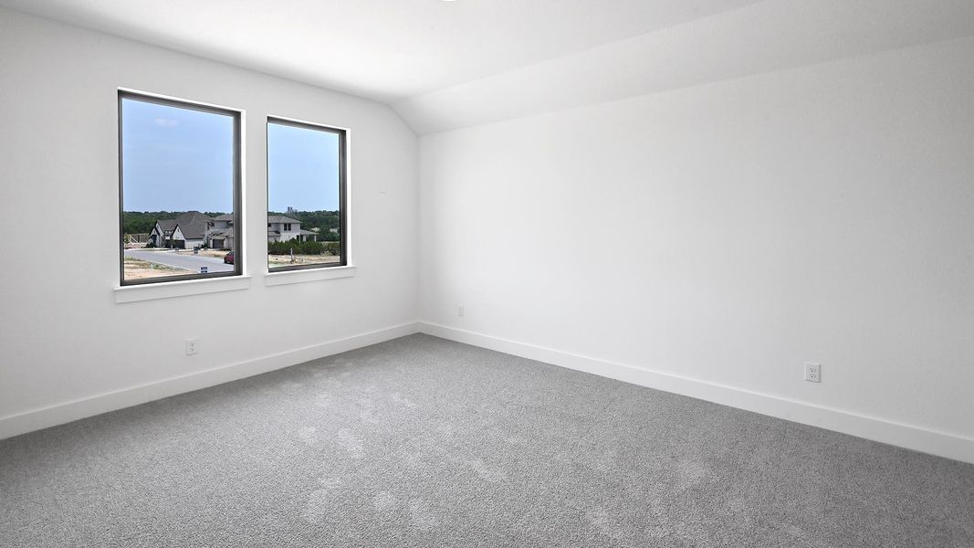 Empty room with carpet, baseboards, and vaulted ceiling Empty room with carpet, baseboards, and vaulted ceiling