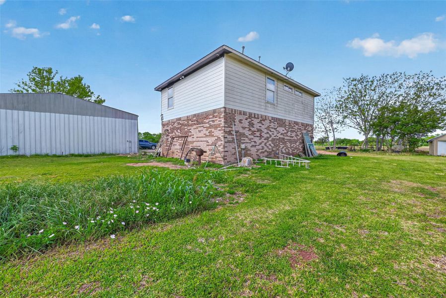 Side and rear exterior view of Property 2 semi-finished residence with adjacent lawn area.