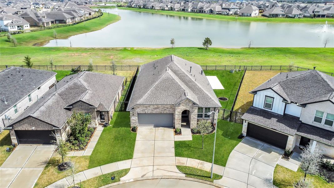 Elevated aerial view showcasing the home’s proximity to the neighborhood lake and surrounding scenic green space.