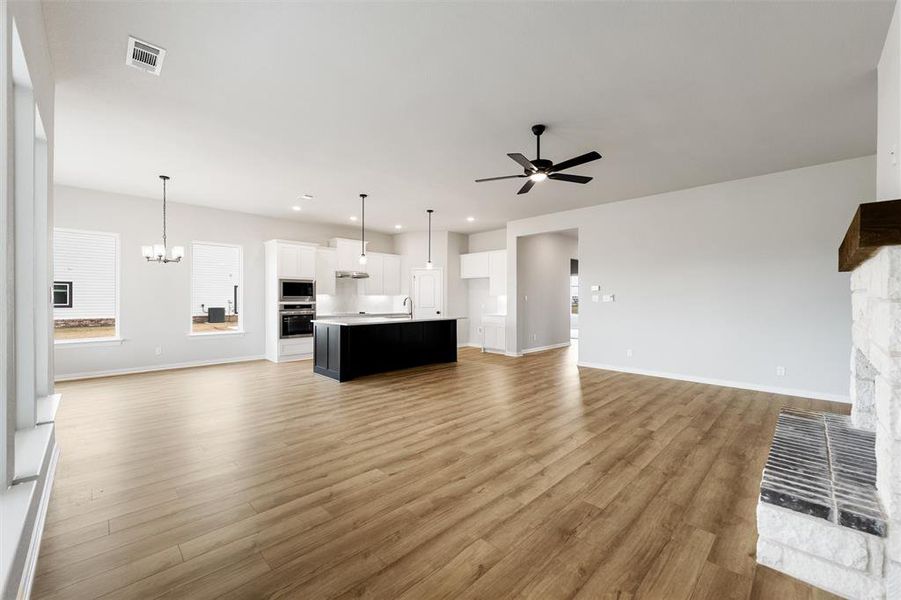Unfurnished living room featuring light wood finished floors, a fireplace, a chandelier, recessed lighting, and ceiling fan Unfurnished living room featuring light wood finished floors, a fireplace, a chandelier, recessed lighting, and ceiling fan