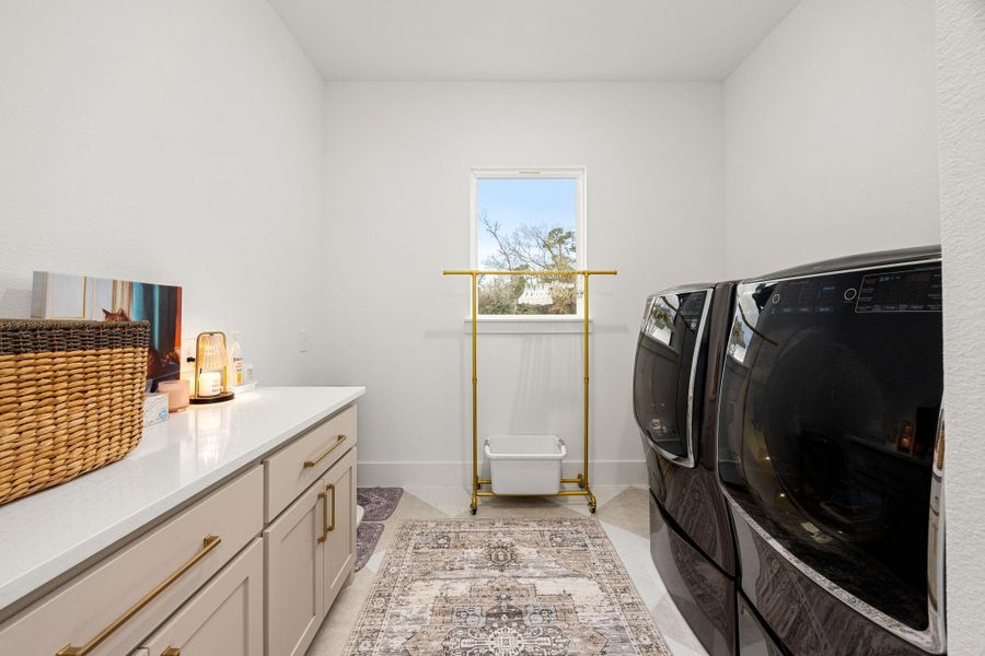 The laundry room is stylishly organized, offering both functionality and aesthetics. It features ample counter space with cabinets for storage