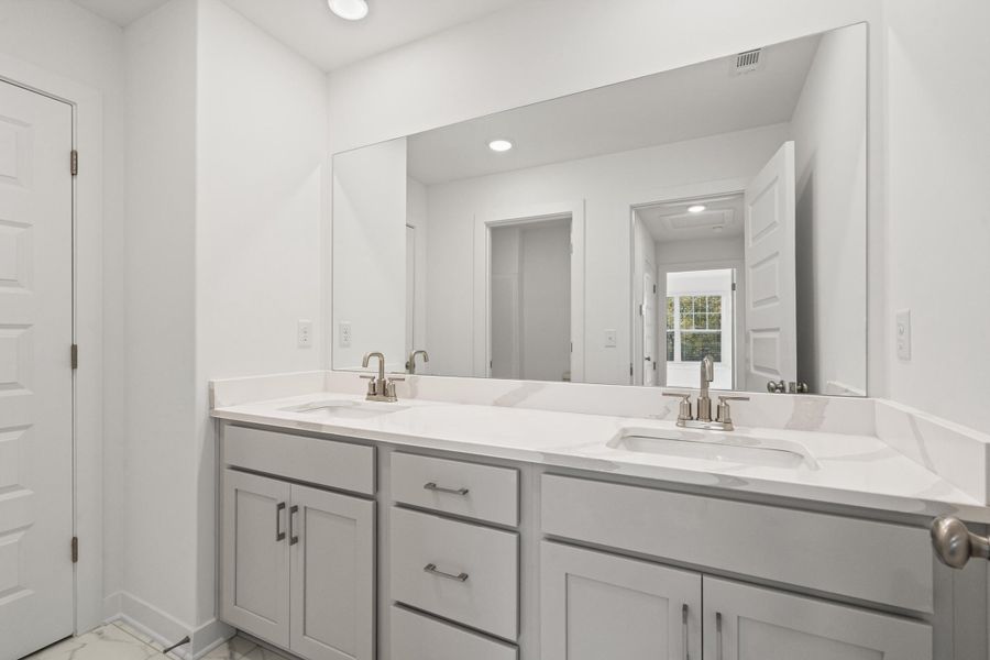 Bathroom with light marble finish flooring, double vanity, and recessed lighting