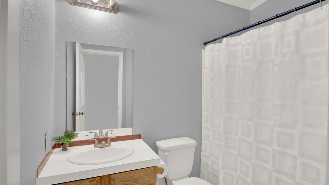 Full bathroom with a shower with shower curtain, vanity, and a textured wall