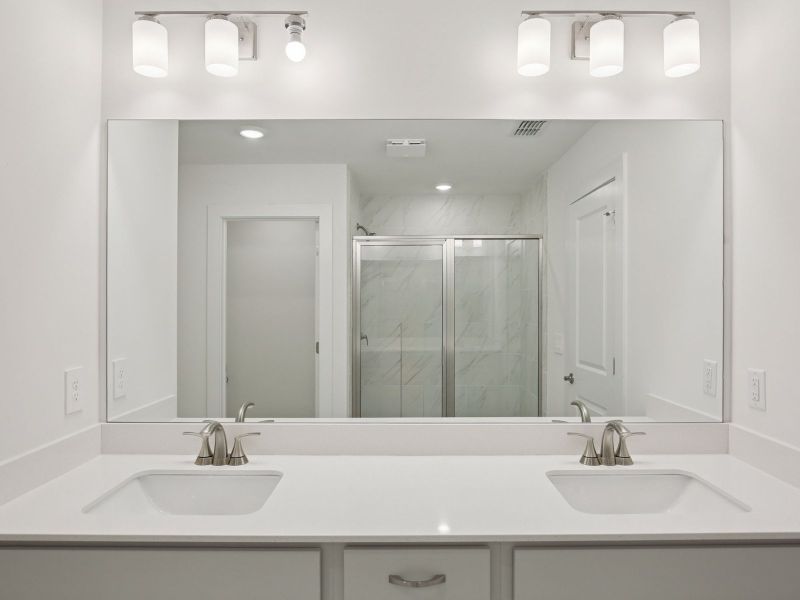 The primary bathroom offers dual vanity sinks and a walk-in shower.