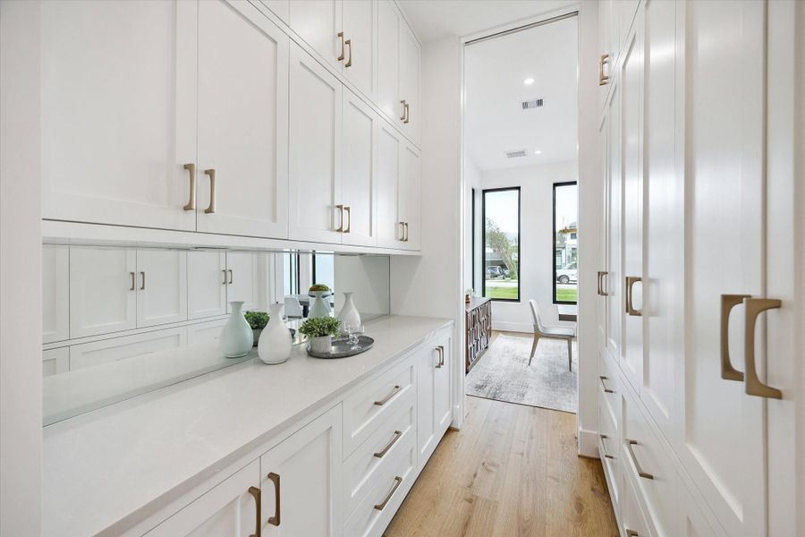 Butler's pantry with storage area and mirrored backsplash seamily located between the kitchen and dining room, the pocket door towards the dining room, offers concealed access for serving and prepping. Butler's pantry with storage area and mirrored backsplash seamily located between the kitchen and dining room, the pocket door towards the dining room, offers concealed access for serving and prepping.