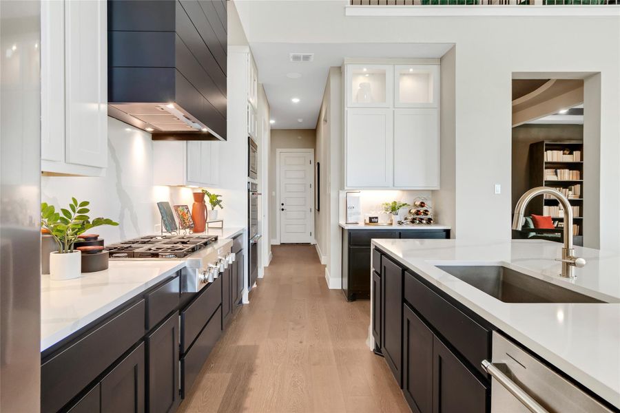 Kitchen with light wood-style flooring, white cabinetry, light countertops, recessed lighting, and wall chimney exhaust hood Kitchen with light wood-style flooring, white cabinetry, light countertops, recessed lighting, and wall chimney exhaust hood